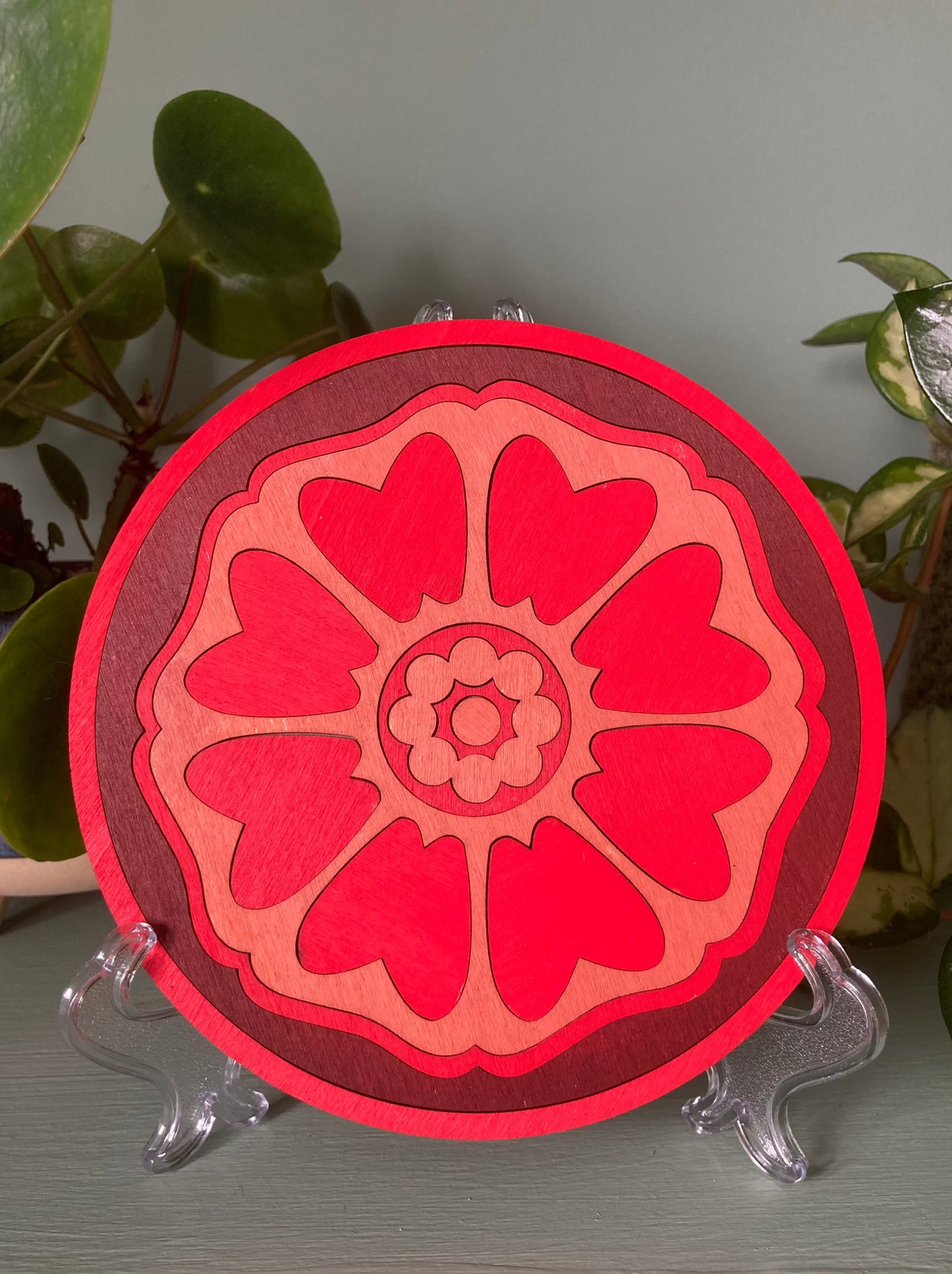 Lotus patterned wooden tile resting on a plastic kickstand. Colour red.