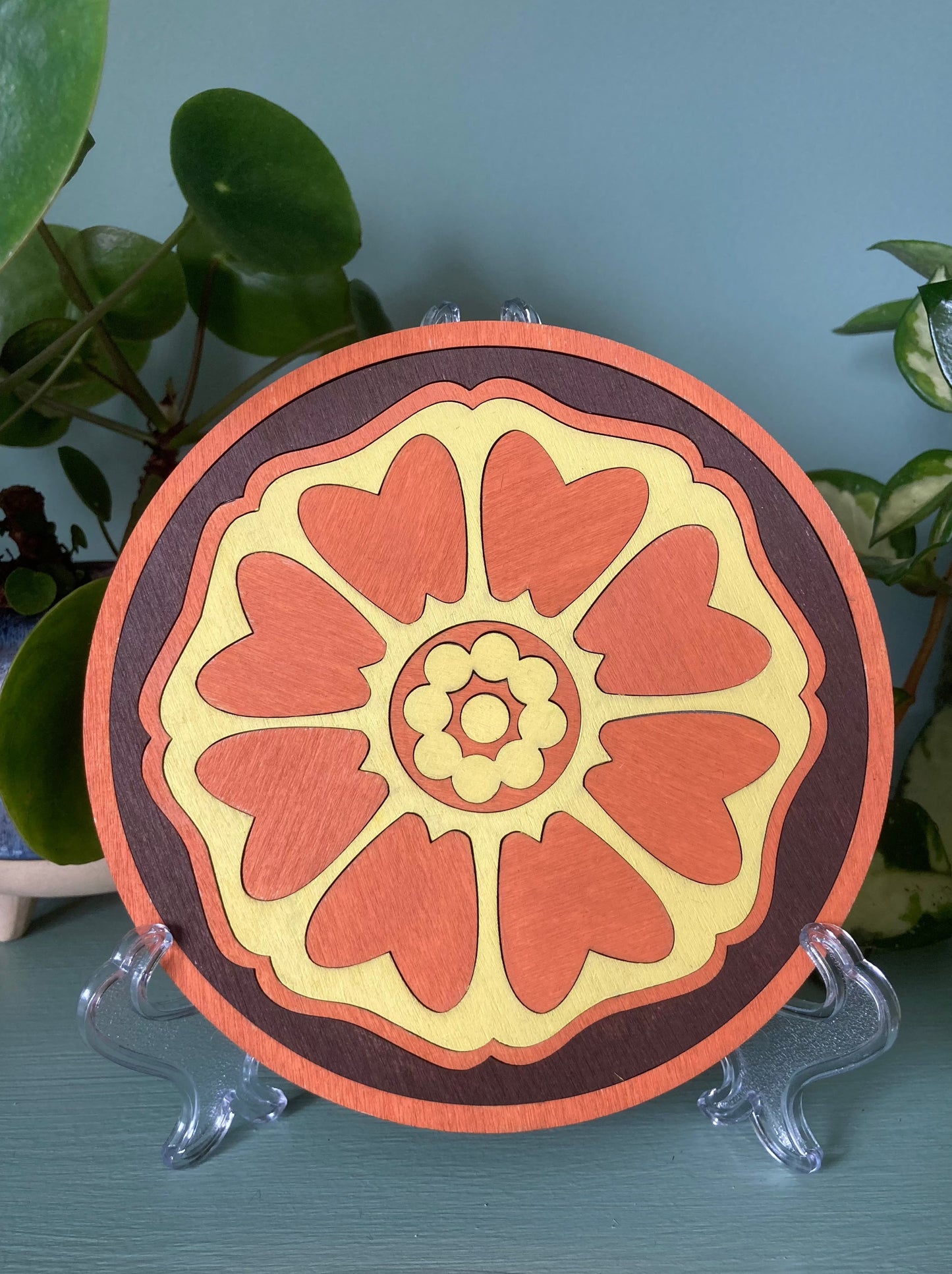 Lotus patterned wooden tile resting on a plastic kickstand. Colour orange