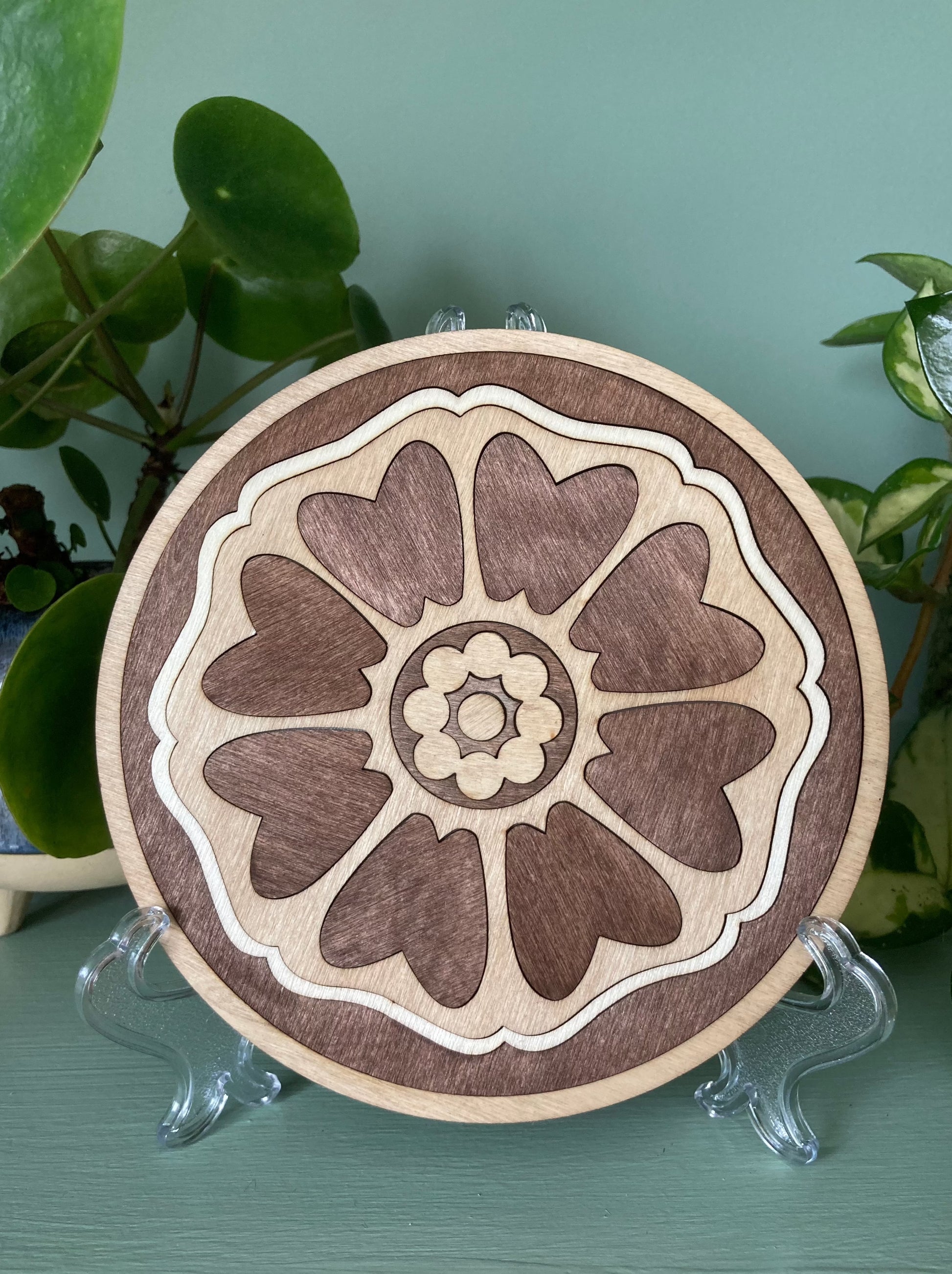 Lotus patterned wooden tile resting on a plastic kickstand. Colour brown.